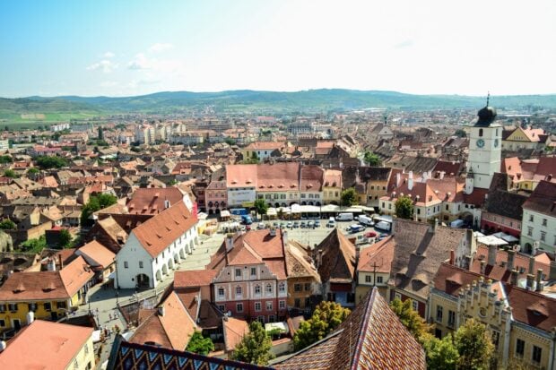 A panoramic view of a Romania town with traditional red rooftops and historic buildings under a clear sky