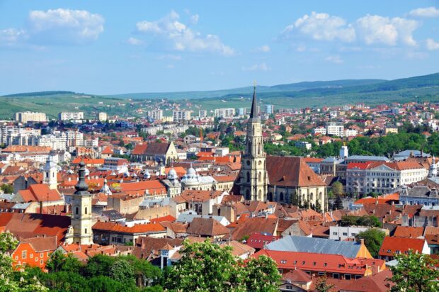 A panoramic view of Romania cityscape featuring historical architecture and lush green hills