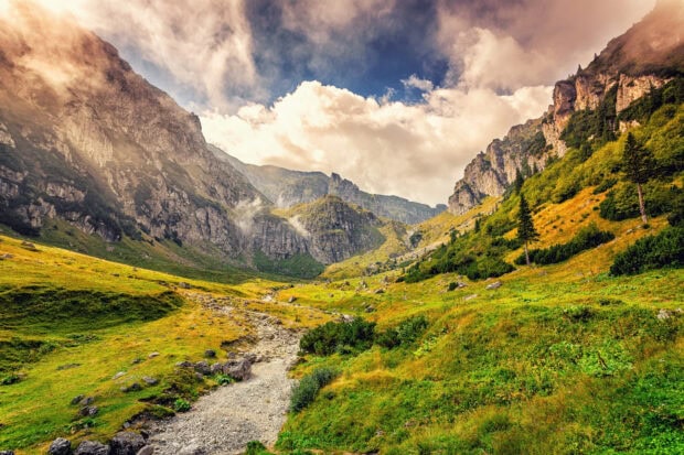 A stunning view of Romania mountain landscape with green valleys and cloudy sky