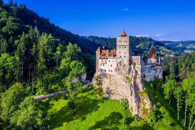 A medieval castle surrounded by lush forest and hills in Romania