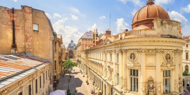 Beautiful historic architecture in Romania with detailed pillars and statues along a sunny street view
