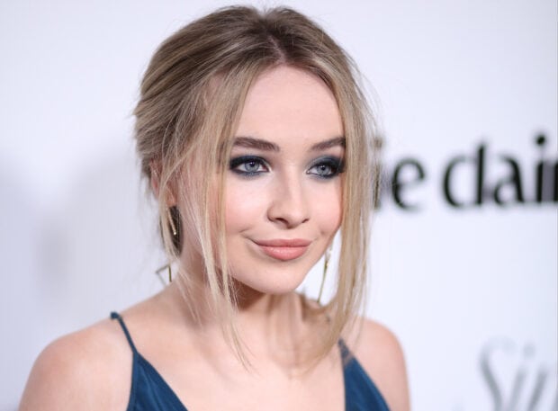 Sabrina Carpenter with smoky eye makeup wearing a dark blue dress at an event