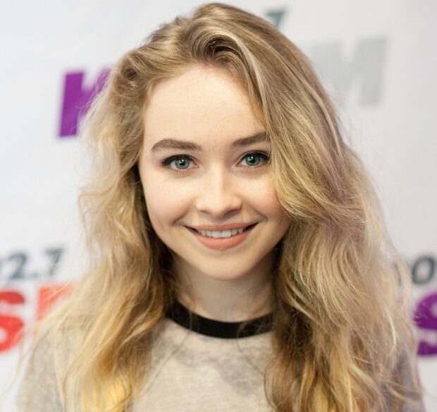 Sabrina Carpenter smiling with wavy blonde hair in a casual top