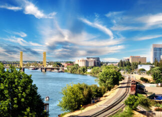 Sacramento city skyline with river forest and bridge under blue sky