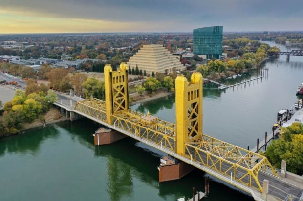 Aerial view of Sacramento with a yellow tower bridge crossing the river and city buildings in the background