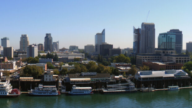 The Sacramento city skyline with riverboats docked along the waterfront in clear daylight