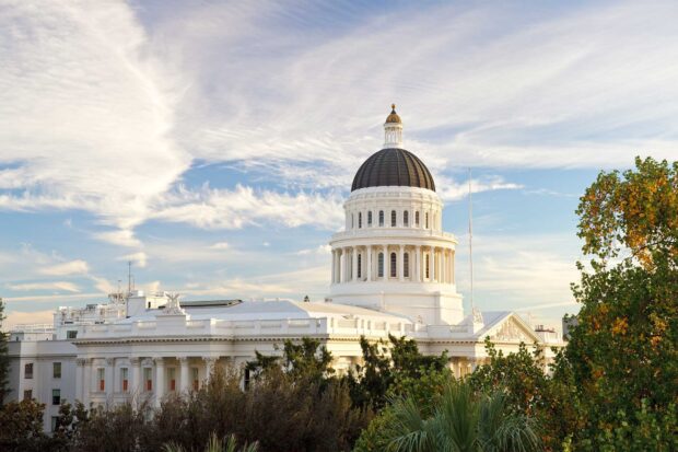 The Sacramento state capitol building surrounded by trees under a partly cloudy sky