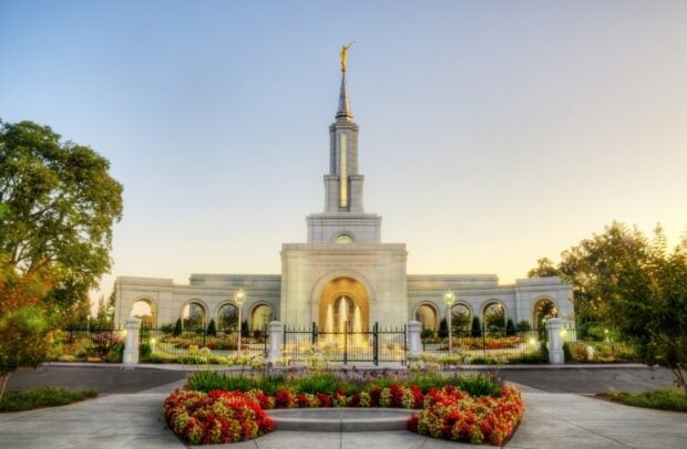 The Sacramento temple surrounded by colorful flowers and green trees at sunset