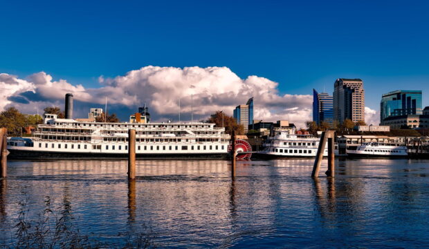 Historic Sacramento riverboats docked with city skyline in the background