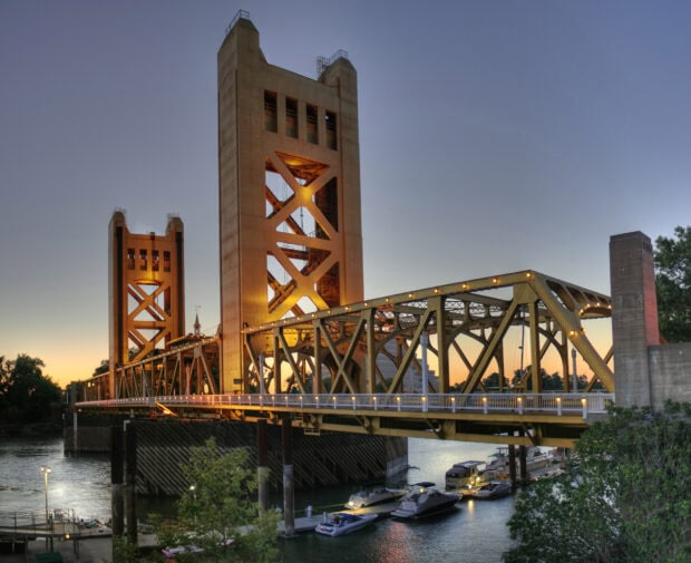 Sacramento bridge illuminated at sunset with boats on river in Sacramento