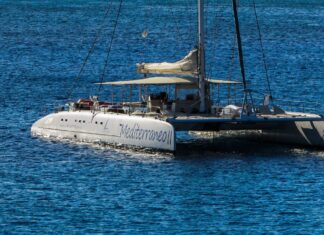 A sail boat floating on calm blue water under clear sunlight