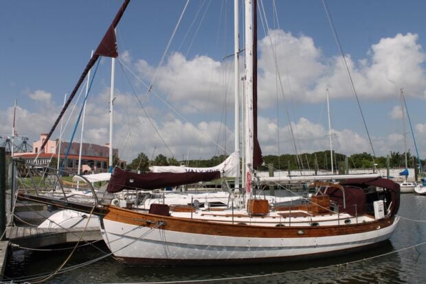 Classic sail boat docked at the marina with wooden details and a partly cloudy sky