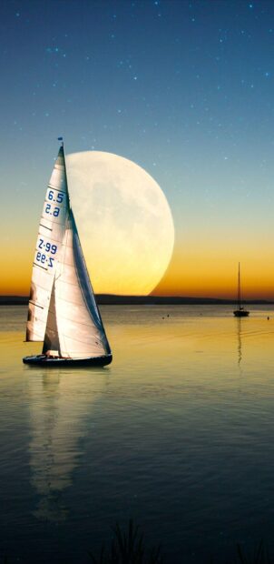 Sail boat sailing on calm water with a large moon in the background at sunset