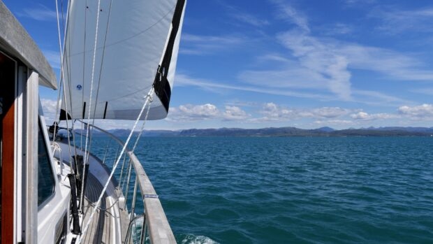 View from the sail boat deck showing ocean and distant mountains under a clear sky