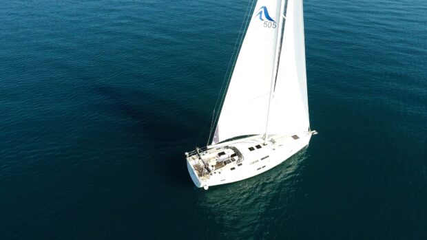 A sail boat is sailing smoothly on deep blue water surrounded by calm sea
