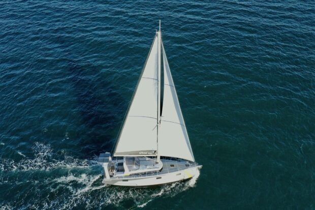 A sail boat sailing smoothly on the deep blue ocean water