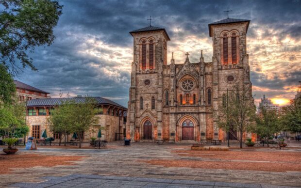 The historic San Antonio Texas cathedral stands under a dramatic cloudy sky at sunset