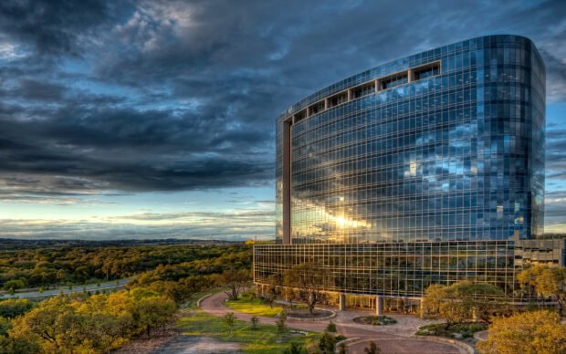 Modern glass building in San Antonio Texas reflecting the cloudy sky and sun