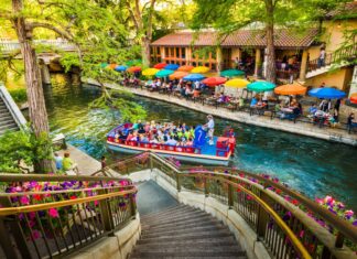 A riverwalk scene in San Antonio Texas with a tour boat and colorful umbrellas along the waterway