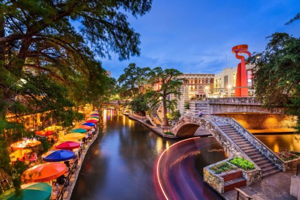 Colorful umbrellas line the riverwalk in vibrant San Antonio Texas at dusk