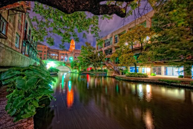 The San Antonio Texas riverwalk with trees and historic buildings illuminated at night