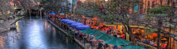 Riverside dining along the San Antonio Texas riverwalk with colorful umbrellas and evening lights