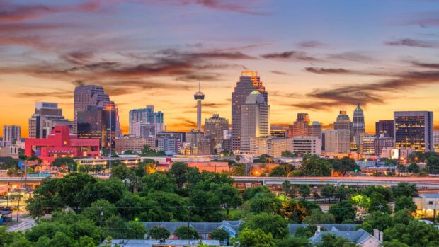 San Antonio Texas city skyline with green trees and colorful sunset sky