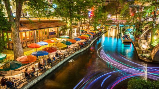 Colorful umbrellas line the riverwalk dining area in a San Antonio Texas scene at night