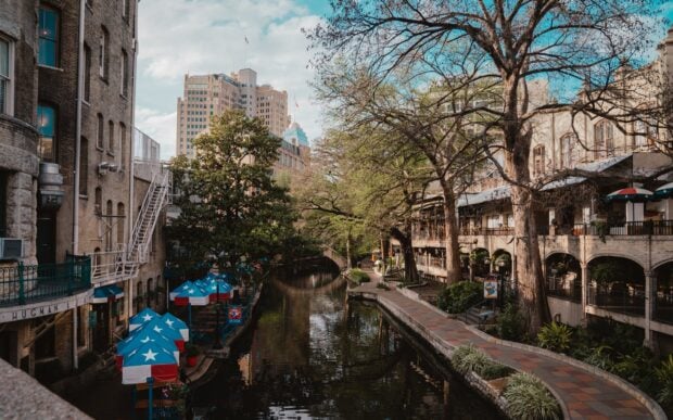 San Antonio riverwalk with colorful Texas star umbrellas and historic buildings in the background