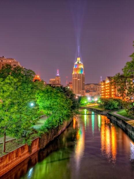 The San Antonio riverwalk at night with colorful city lights reflecting in the water