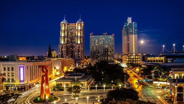 Nighttime cityscape of San Antonio Texas featuring illuminated skyscrapers and streets