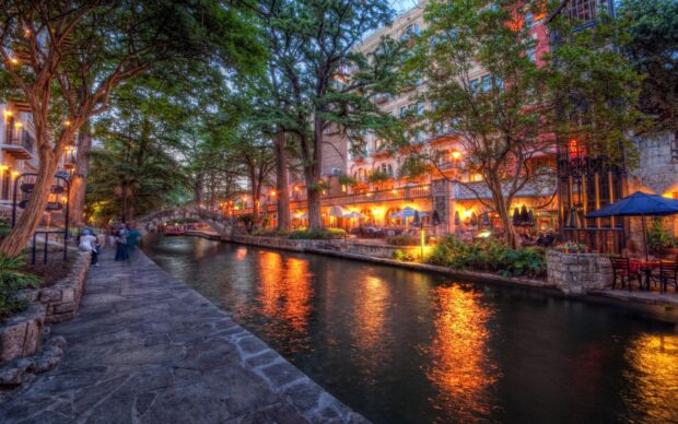 Evening view of San Antonio Texas riverwalk with illuminated trees and buildings