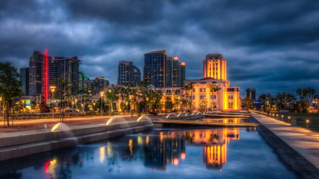 Cityscape of San Diego California reflecting over water under cloudy sky at dusk