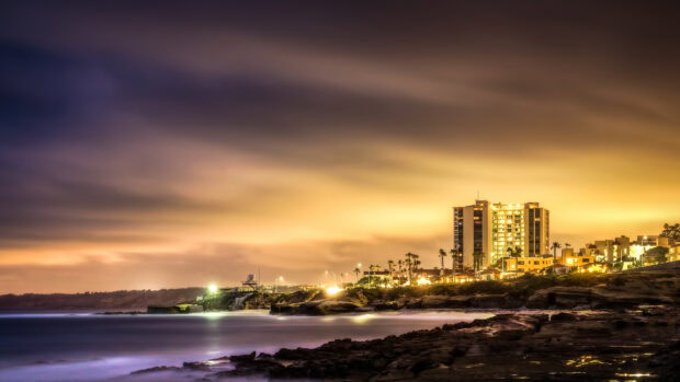 San Diego coastline at night with illuminated buildings and calm ocean waters
