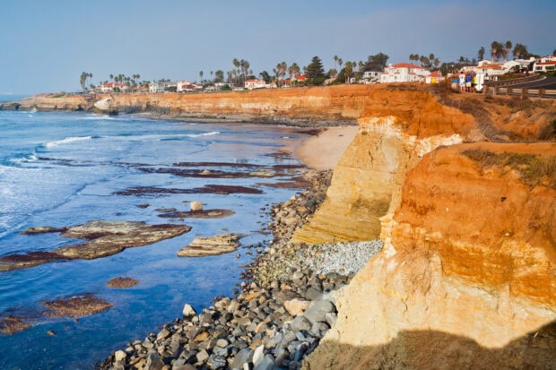 A scenic coastline of San Diego California with cliffs and waves under a clear sky
