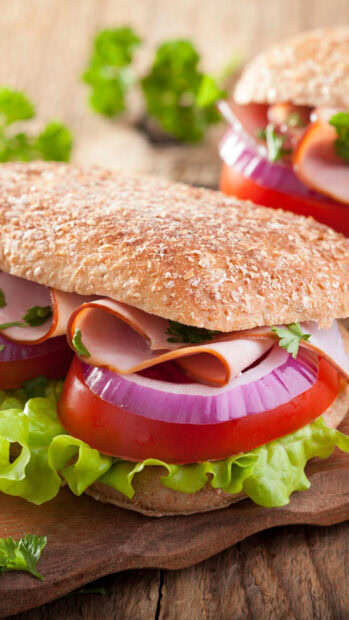 Fresh sandwich with ham tomato lettuce and onion on whole grain bread