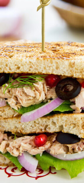 A fresh sandwich with tuna lettuce onion and olives on toasted bread