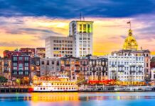 Historic Savannah Georgia cityscape with riverboat and colorful sunset sky