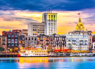 Historic Savannah Georgia cityscape with riverboat and colorful sunset sky