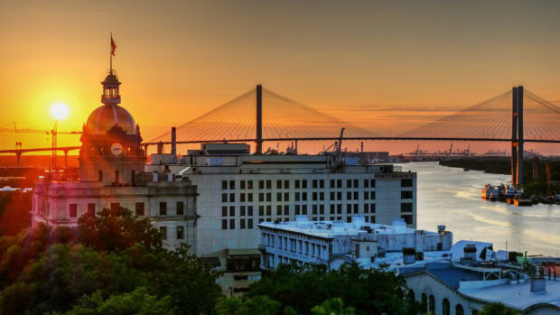 Savannah Georgia cityscape with historic buildings and a river at sunset