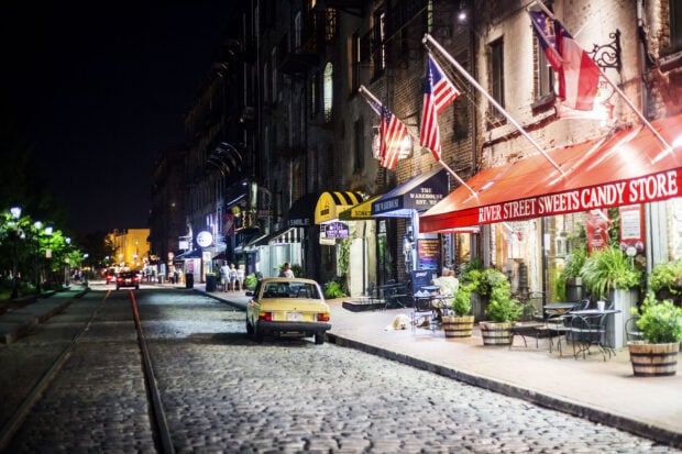 Historic Savannah street with vintage car and illuminated candy store at night