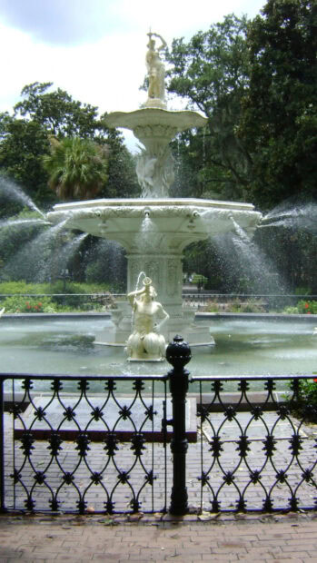 Marble statues water fountain in Savannah Georgia park with greenery in background