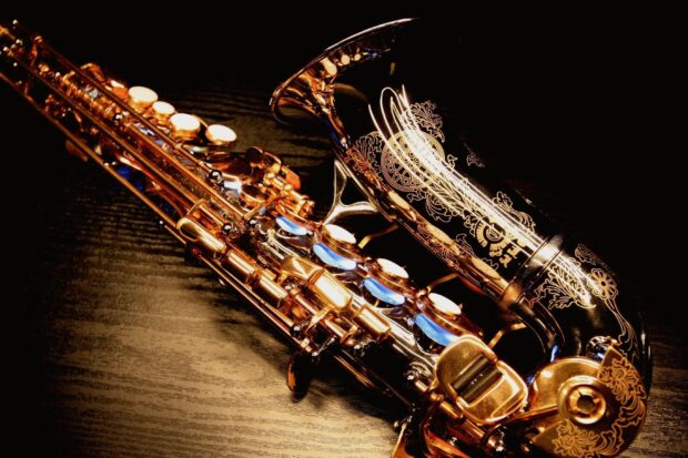 A close up of a saxophone with intricate floral engravings on a wooden surface