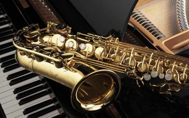 A close up view of saxophone keys resting on piano keys with intricate details visible