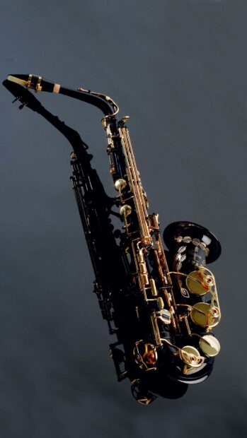 A black saxophone with gold keys and intricate details on a dark background