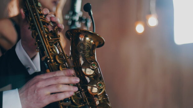 A musician playing saxophone with detailed keys and hands in focus
