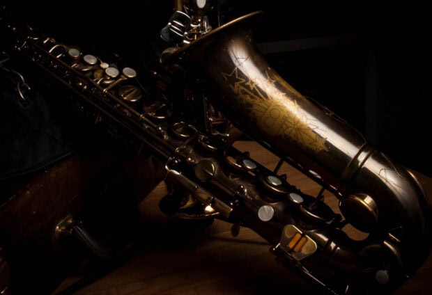 A close up view of a vintage saxophone with detailed engravings resting on a wooden surface