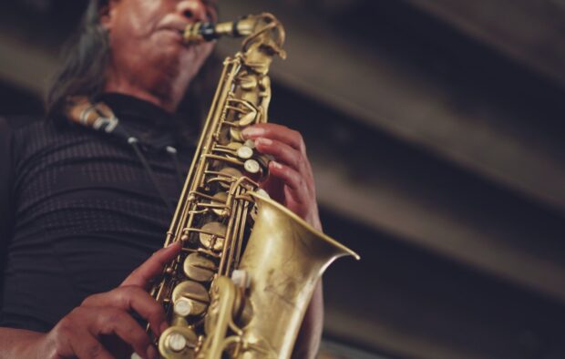 Musician playing saxophone with detailed saxophone keys and brass instrument close up