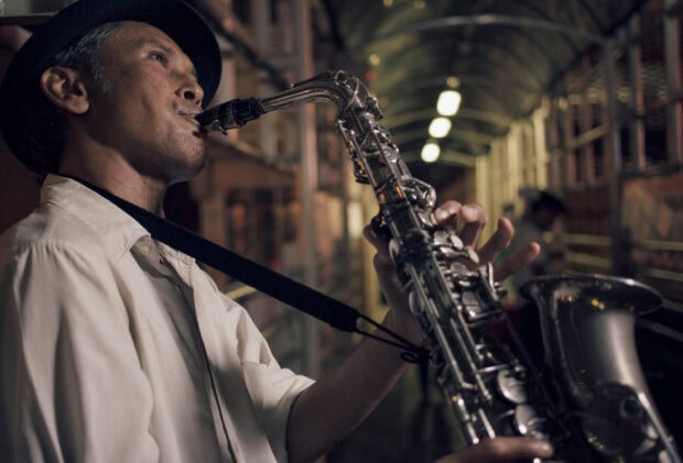 A man playing saxophone in a dimly lit corridor