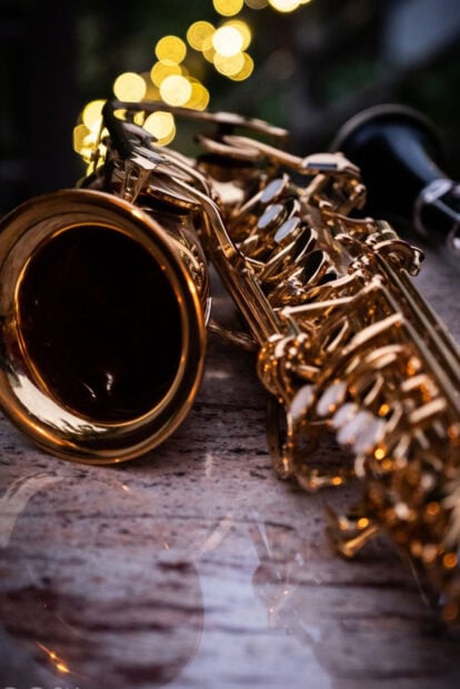Close up of a saxophone lying on a marble surface with blurred lights in the background
